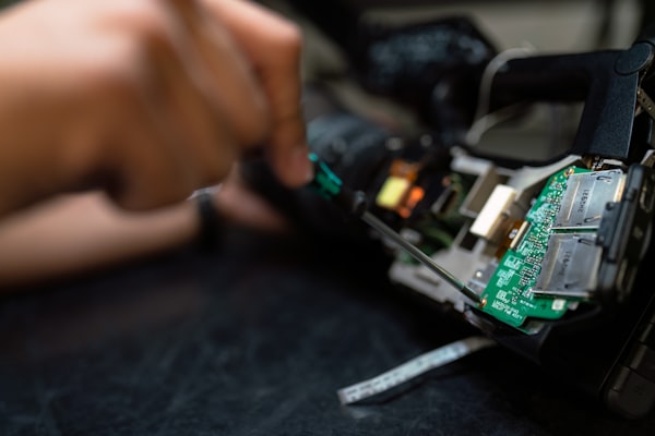 A child's hands assembling a small robot from a circuit board and chassis